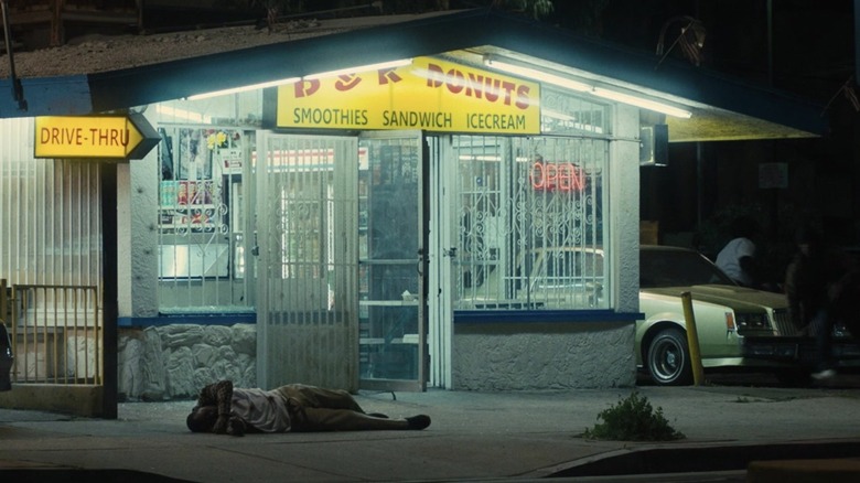 Man lying on the ground in front of a brightly-lit convenience store