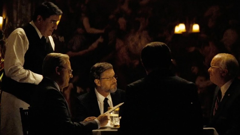 Christian Bale as Dick Cheney sitting with colleagues in fancy restaurant