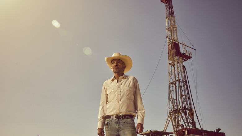 Tommy stands before a large oil derreck in "Landman"