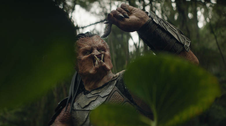 Dek holding up a bug in "Predator: Badlands" (2025)