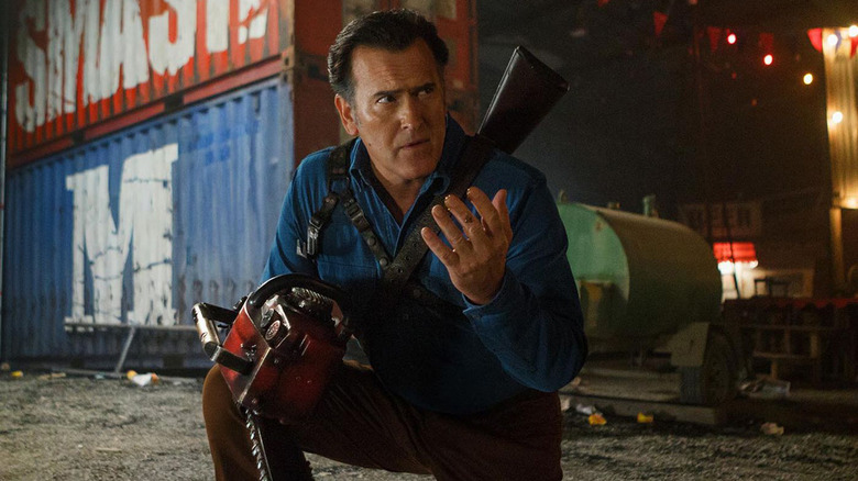 Ash Williams kneeling in front of shipping containers