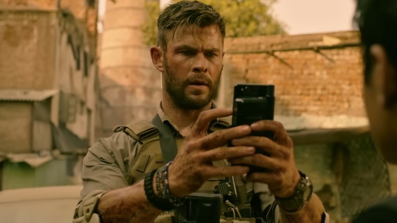 Tyler Rake holds up his phone in "Extraction" (2020)
