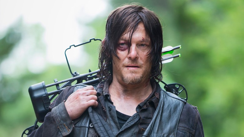 Daryl walking with bow and arrow