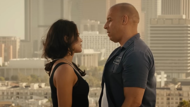 Letty and Dom stand close together on top of a building overlooking a city