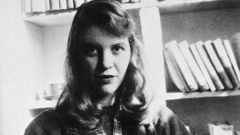 Sylvia Plath seated in front of a bookshelf