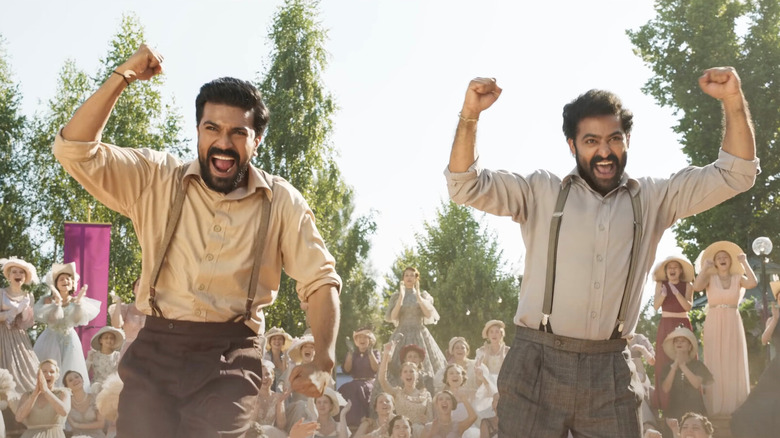 Ram and Bheem pump fists dancing as women cheer them on in "RRR" (2002)