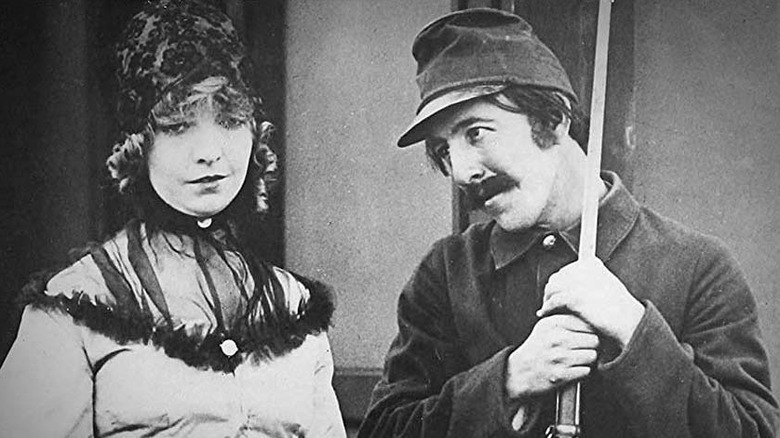 A soldier holding a gun smiles at a woman in "The Birth of a Nation" (1915)