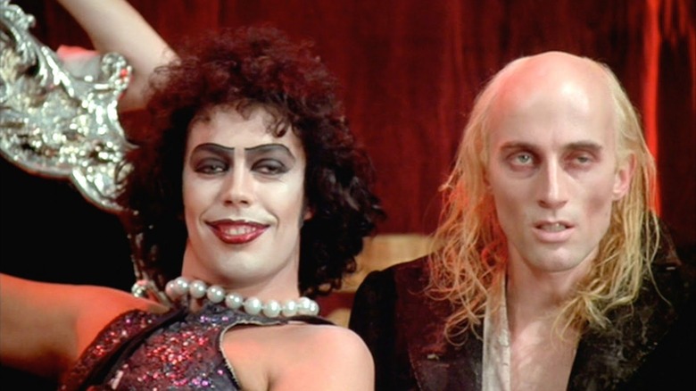 Frank smiles leaning next to Riff-Raff in "The Rocky Horror Picture Show" (1975)