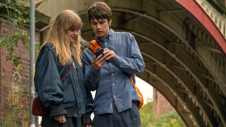 Emily looking at Owen's phone as he gets a text from the real Emily in Finding Emily (2026)