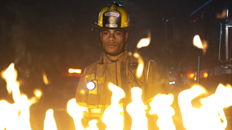 Jake Crawford staring seriously behind flames