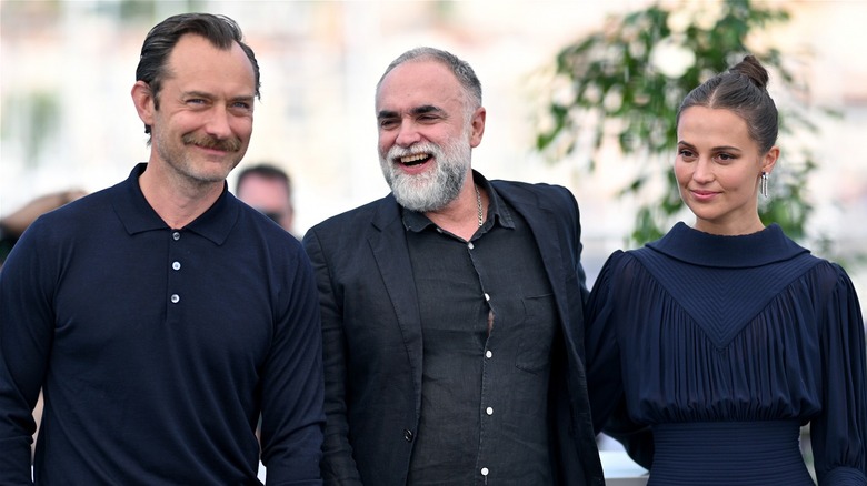 Jude Law, Karim Aïnouz, and Alicia Vikander smiling