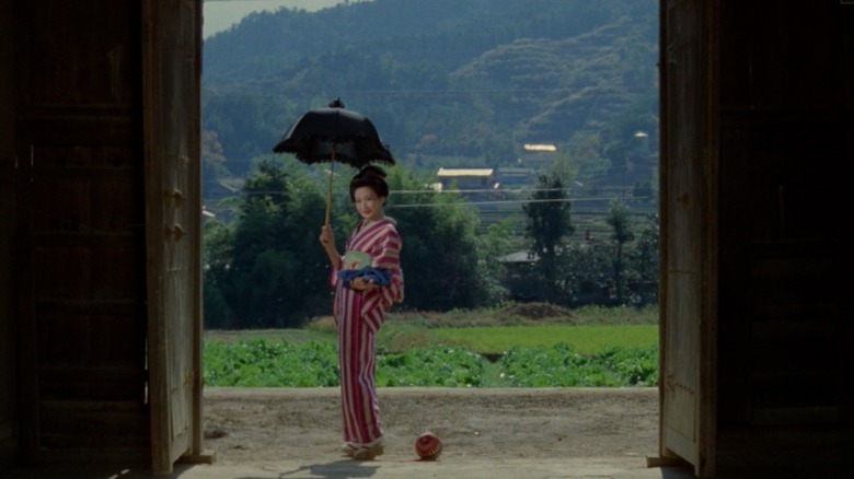Woman standing at door frame and holding an umbrella in Grass Labyrinth