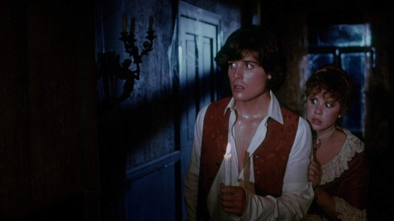 Two college students looking scared in a dark hallway in "Hell Night"