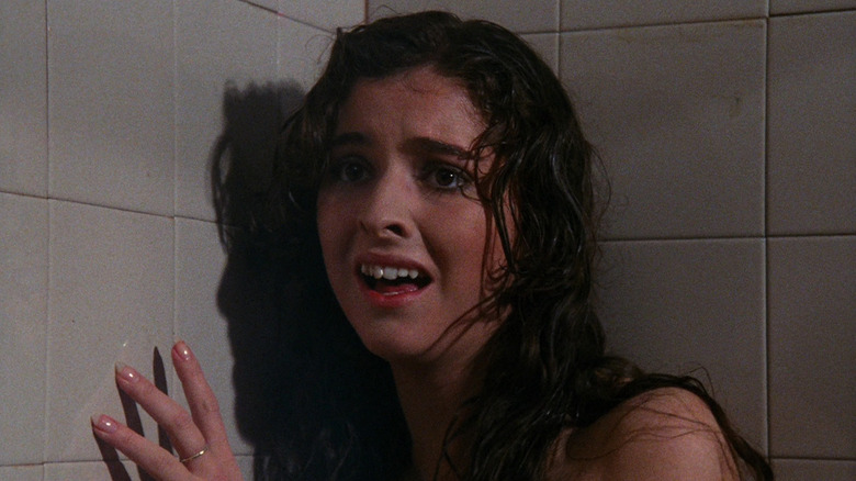 A frightened girl hiding in the corner of a shower in "Pieces"