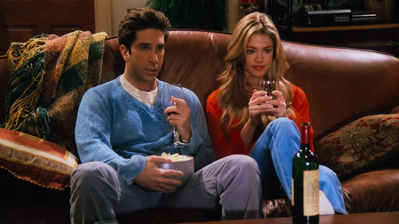 Ross and Cassie Geller sitting on the couch while holding wine in "Friends"