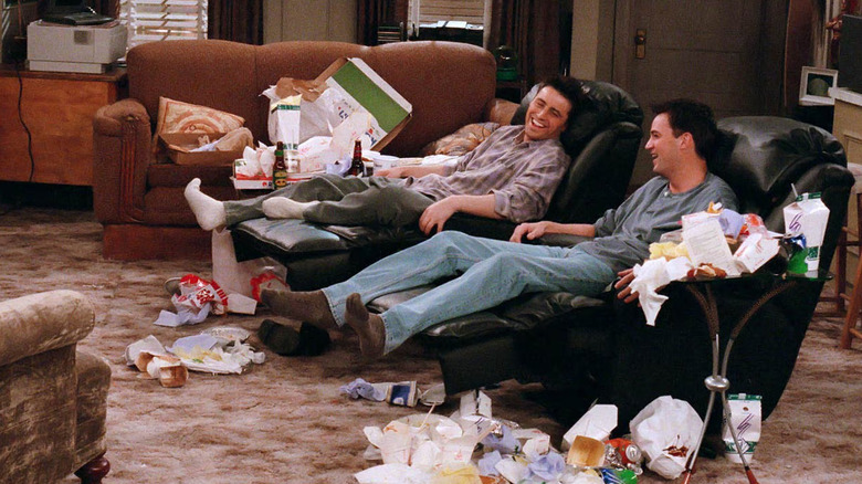 Joey and Chandler sitting in their recliners and laughing, surrounded by piles of takeout containers in Friends
