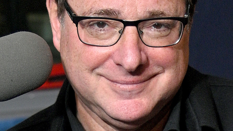 Bob Saget with glasses and a microphone