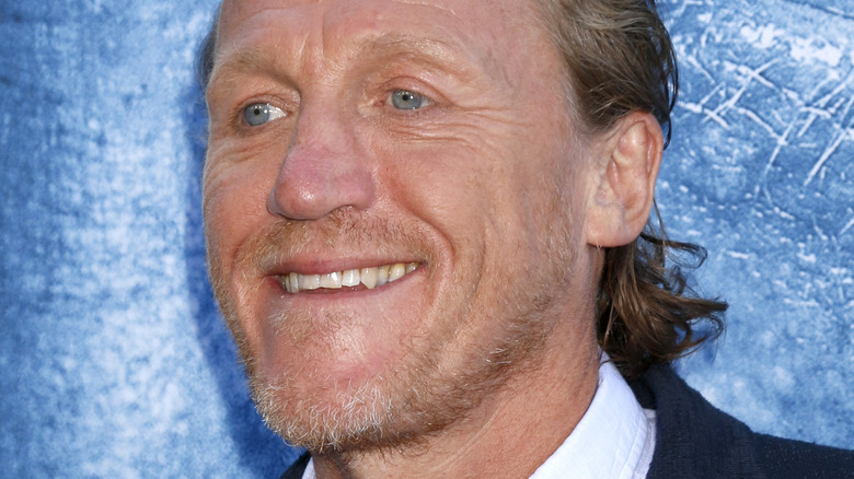 Jerome Flynn smiling in front of blue background