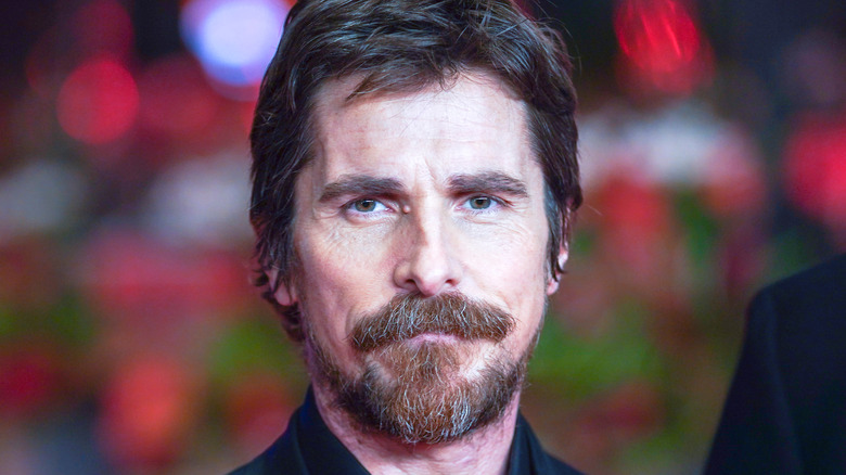 Christian Bale smiling near red lights