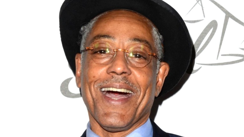 Giancarlo Esposito smiles while wearing a hat