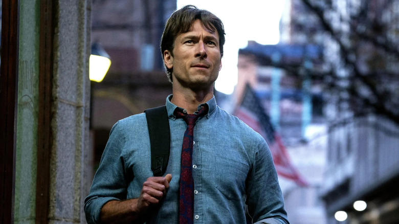 Becket out on the street looking at something in How to Make a Killing