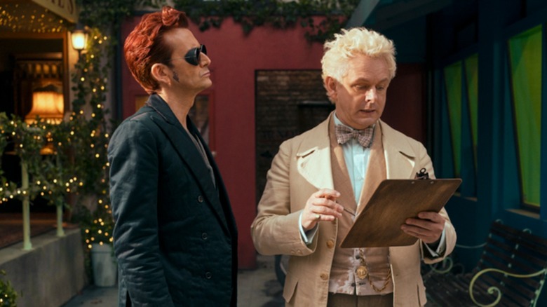 Crowley looking at Aziraphale holding clipboard