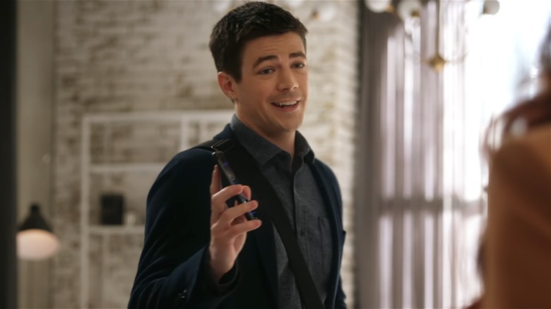 Barry Allen smiles and holds a phone 