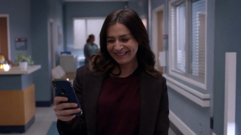 Amelia Shepherd smiling at her phone 