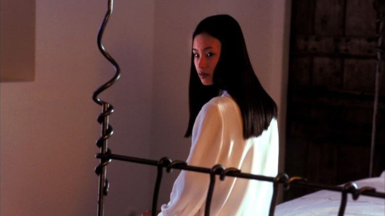 Asami sits ominously on the end of her bed in "Audition" (1999)