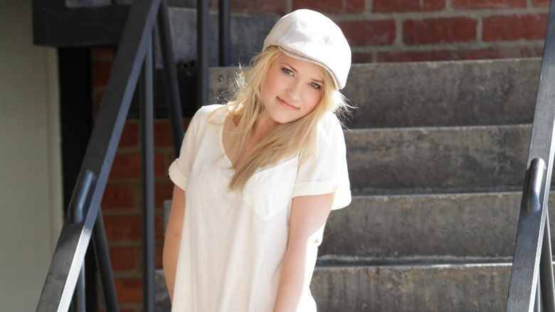 Emily Osment in white standing on steps