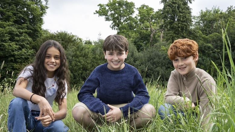 Arabella Stanton, Dominic McLaughlin, and Alastair Stout kneeling in grass