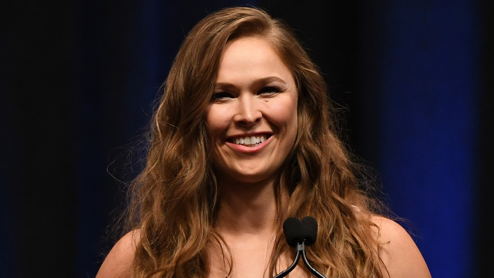 Ronda Rousey smiling in front of microphone