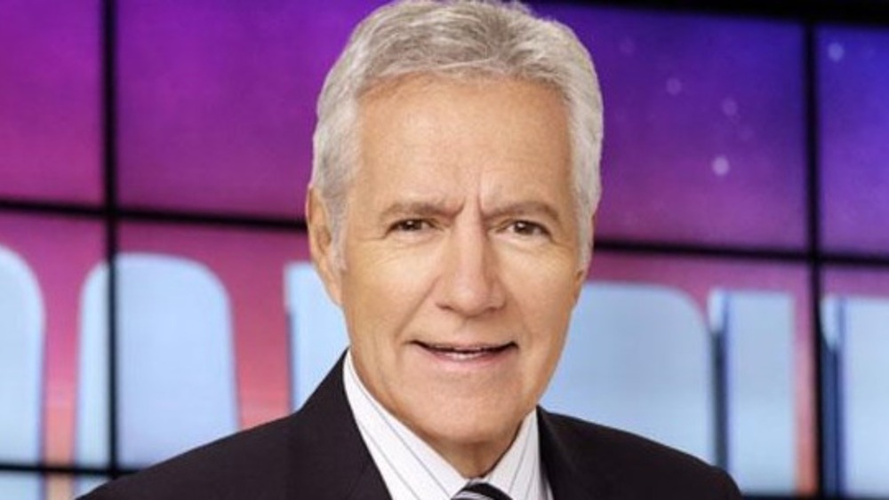 Alex Trebek stands on the Jeopardy set