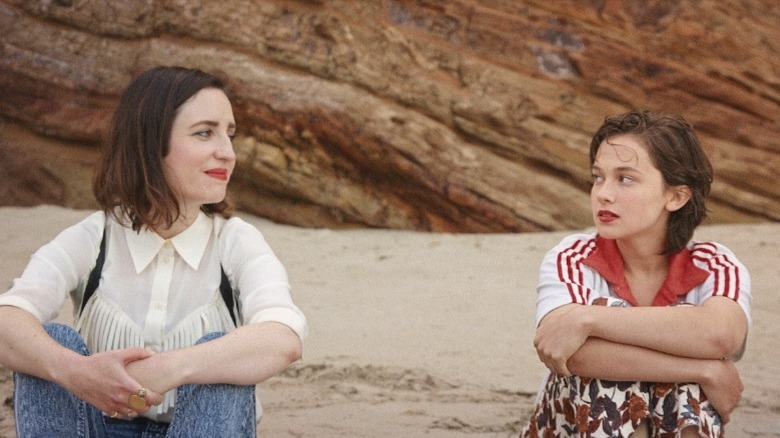 Liza and her younger self sitting at a beach