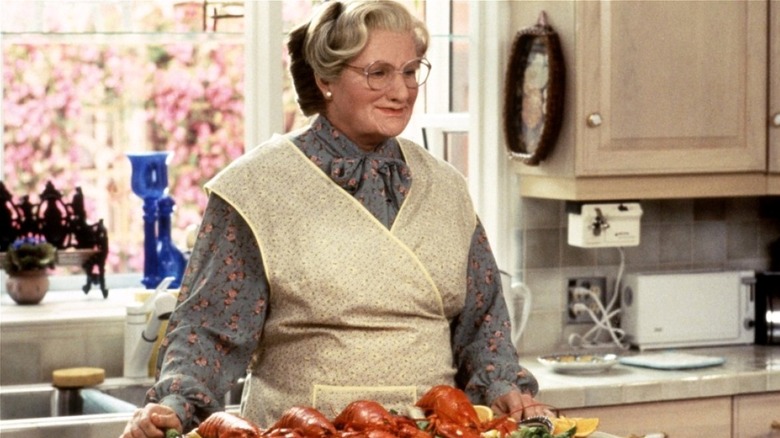 Mrs. Doubtfire standing in kitchen by cooked lobsters