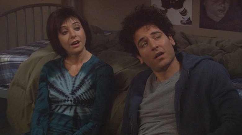 Ted and Lily lean against a bed