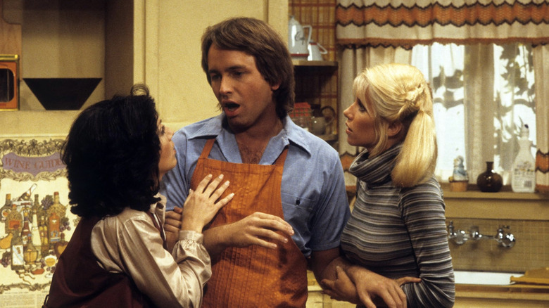 Janet, Jack, and Chrissy standing together in the kitchen in "Three's Company"