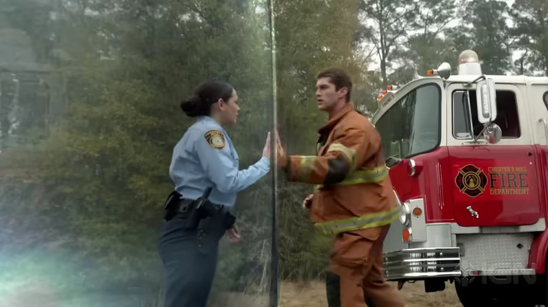 A cop and a fireman in Under the Dome placing their hands on either side of an invisible dome