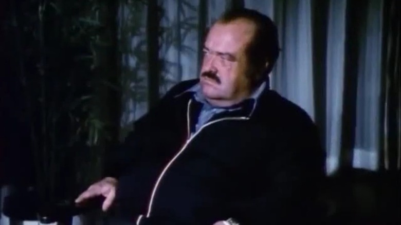 William Conrad as Frank Cannon, sitting in a dark room, on Cannon