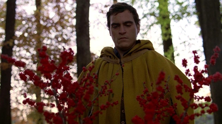 Lucius wearing yellow robe looking at red plant