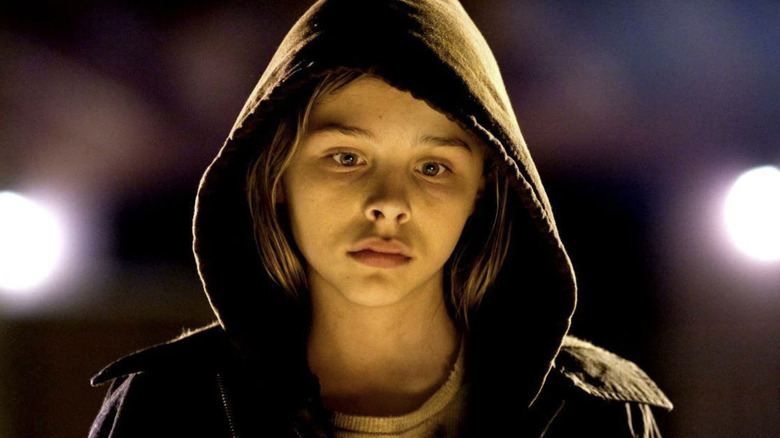 Abby looks down while wearing a hoodie in "Let Me In" (2020)