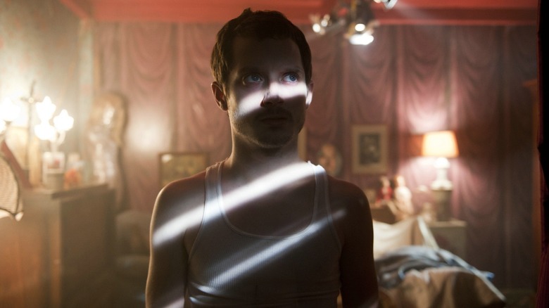 Frank standing in room with light coming in through the blinds in "Maniac" (2012)