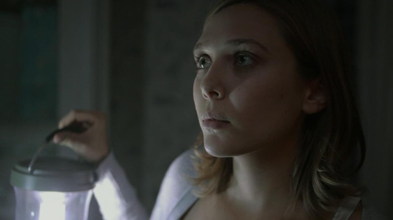 A wary Sarah holds an electric lantern in "Silent House" (2011)