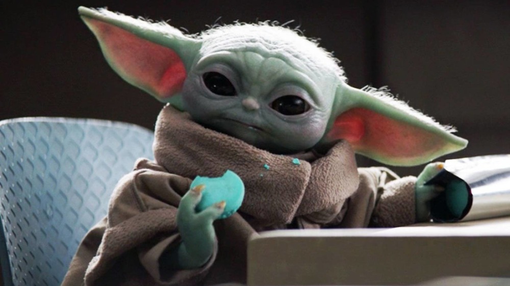 Baby Yoda, also known as Grogu, eats blue macarons on The Mandalorian