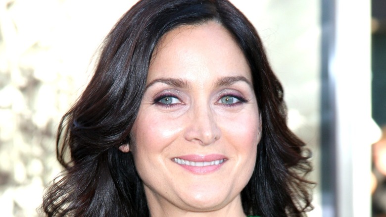 Carrie-Anne Moss smiling for photographers