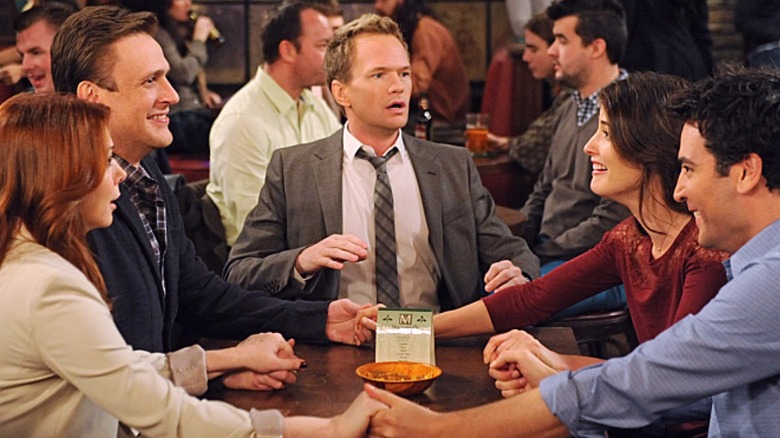 Lily, Marshall, Barney, Robin, and Ted around a table in "How I Met Your Mother"