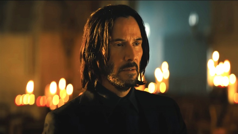 John Wick sitting in candle lit church