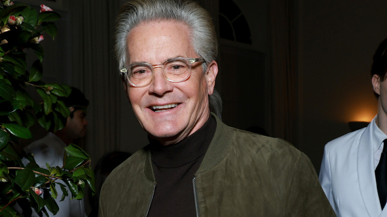 Kyle MacLachlan smiling in a green jacket