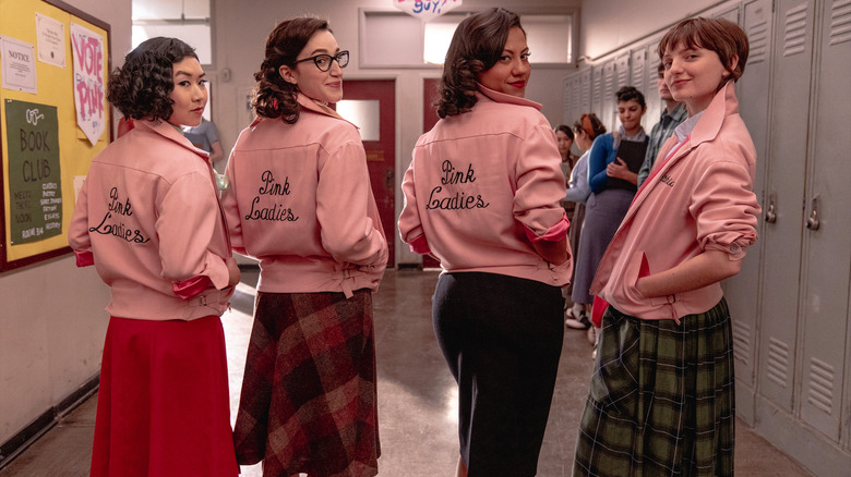 Four women with pink tops in school hallway