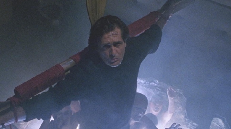 Father Damian Karras hangs on a cross in a dark, foggy space